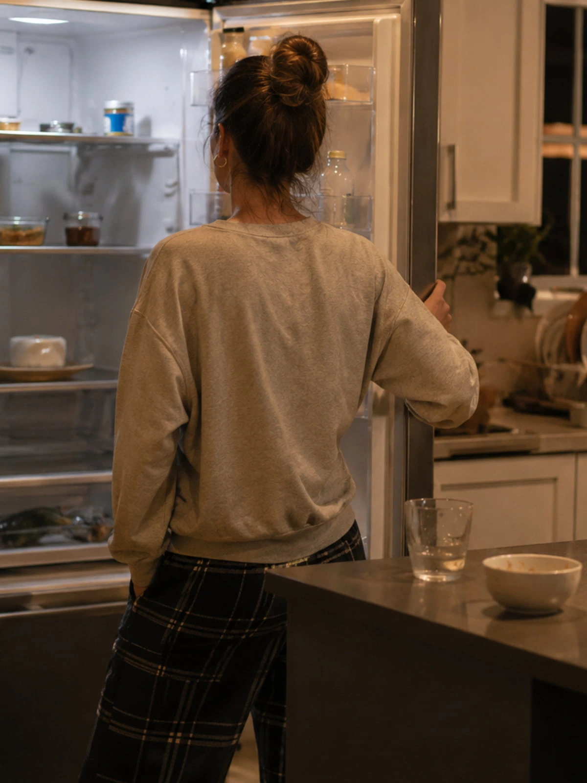 Tired person standing in front of an open fridge at 6 PM